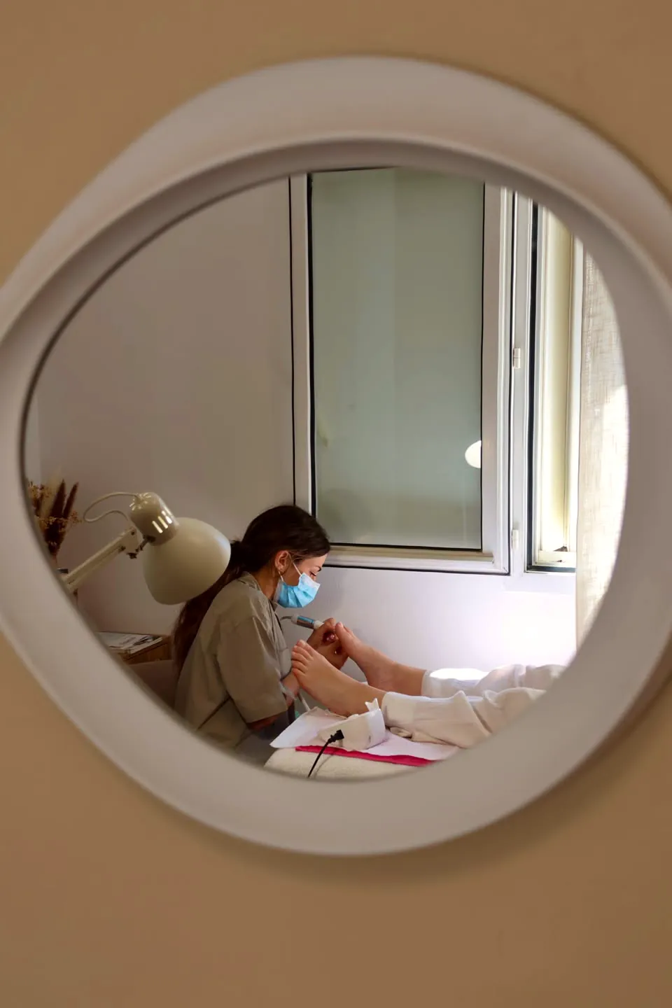 Cloé au travail, vue dans le miroir rond de l'institut Eden Rose à La Garde
