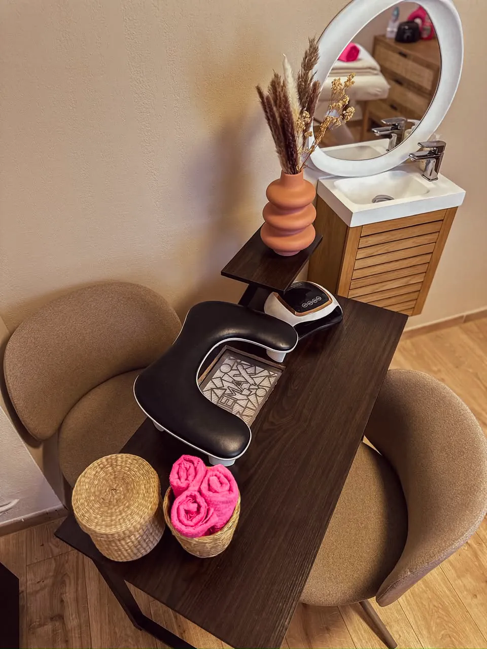 L'espace onglerie sous le miroir rond, avec la lampe et les serviettes roses
